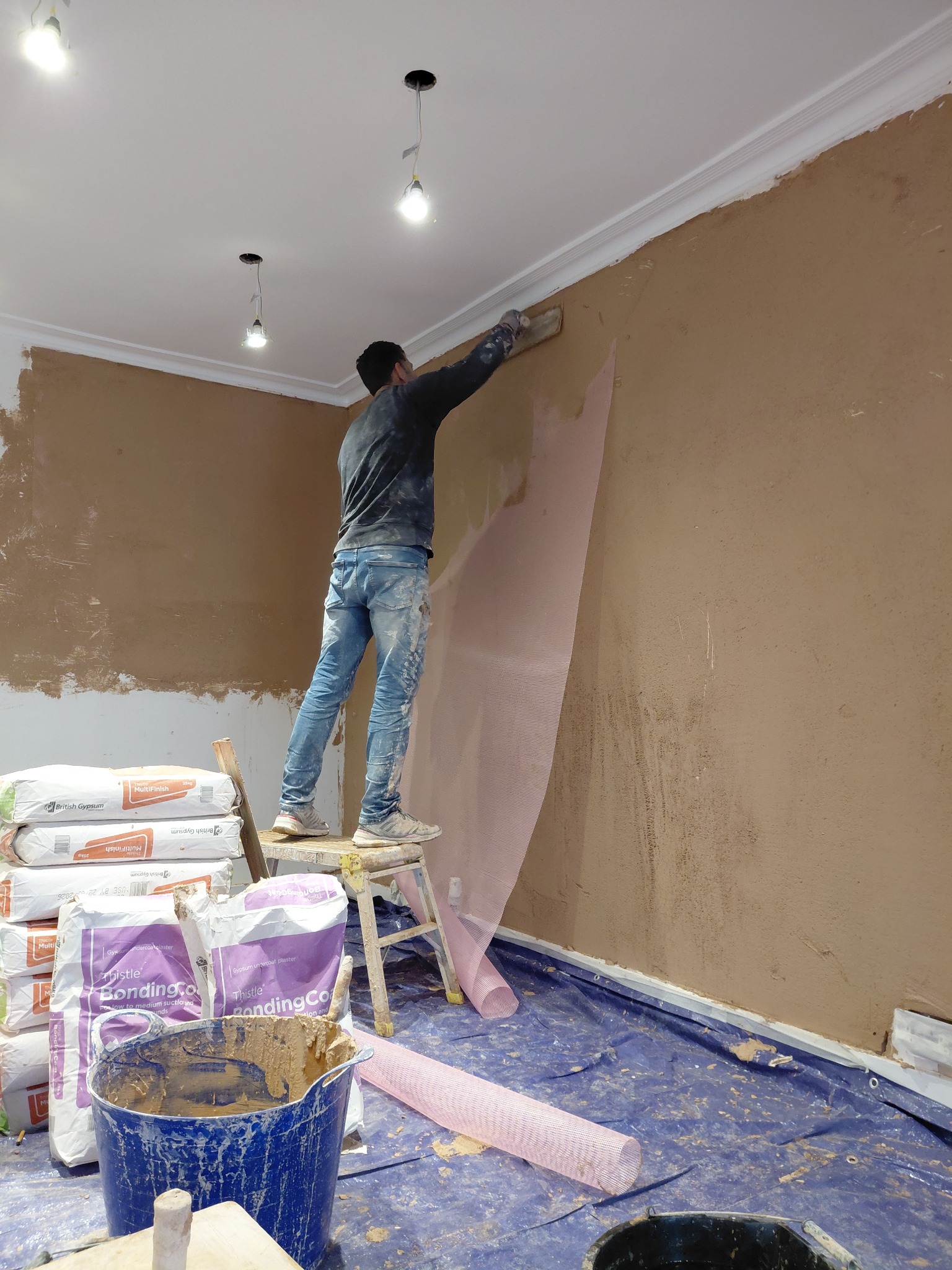 Plasterer applying reinforcement mesh to an interior wall