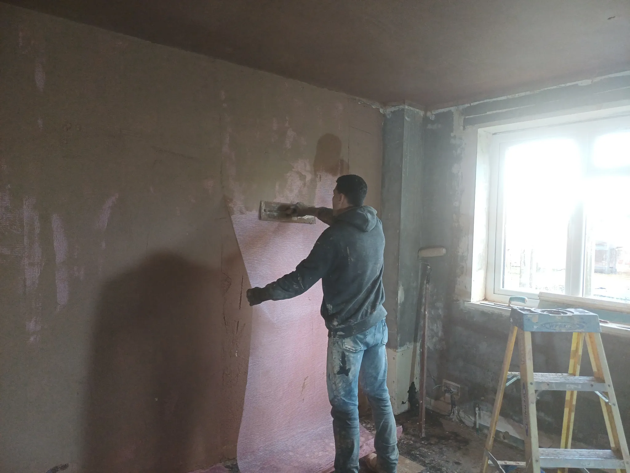 Plasterer working with reinforcing mesh on an interior wall at Barons Court