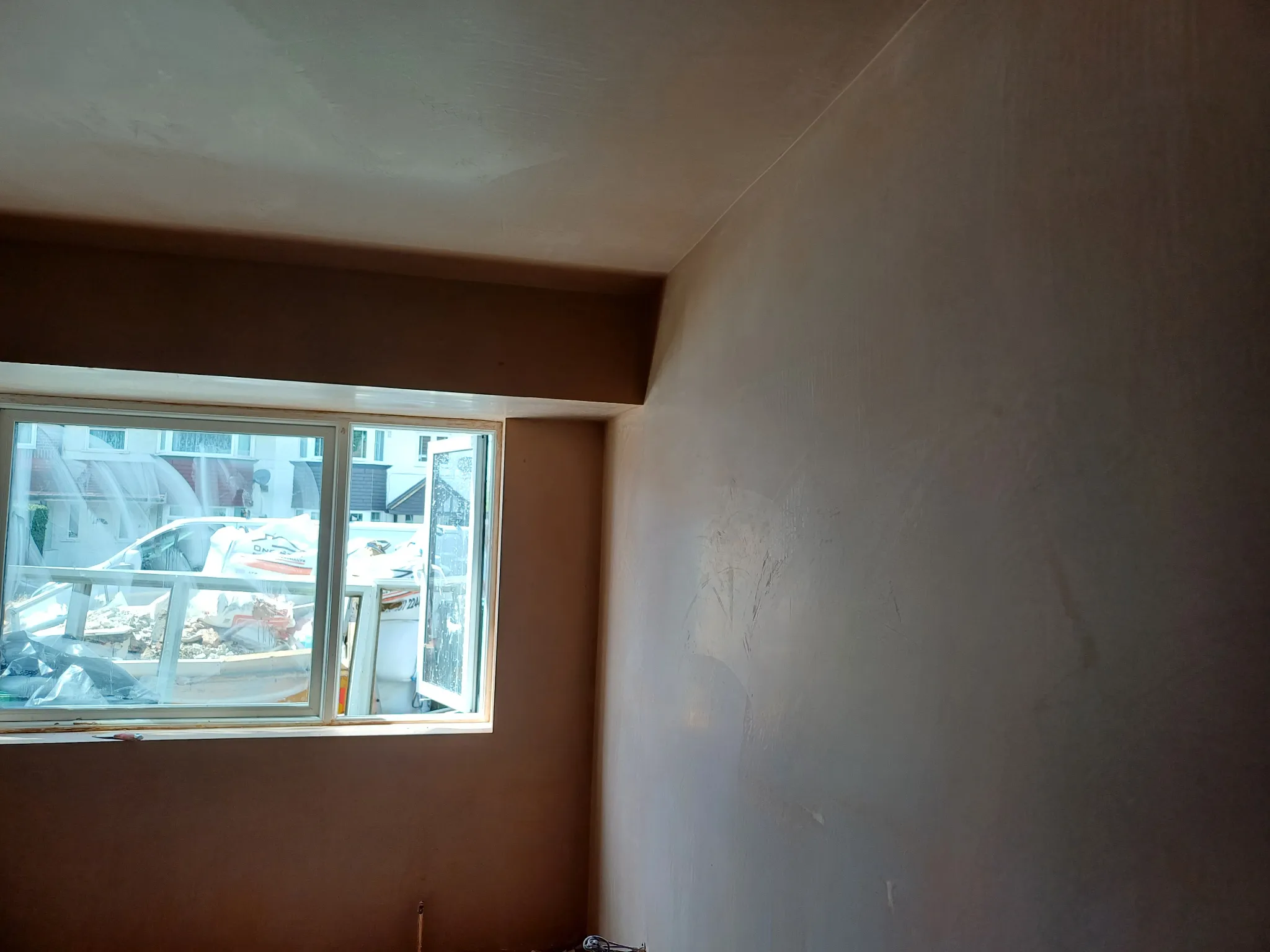 Fresh plaster on the walls and ceiling of a room with a bay window