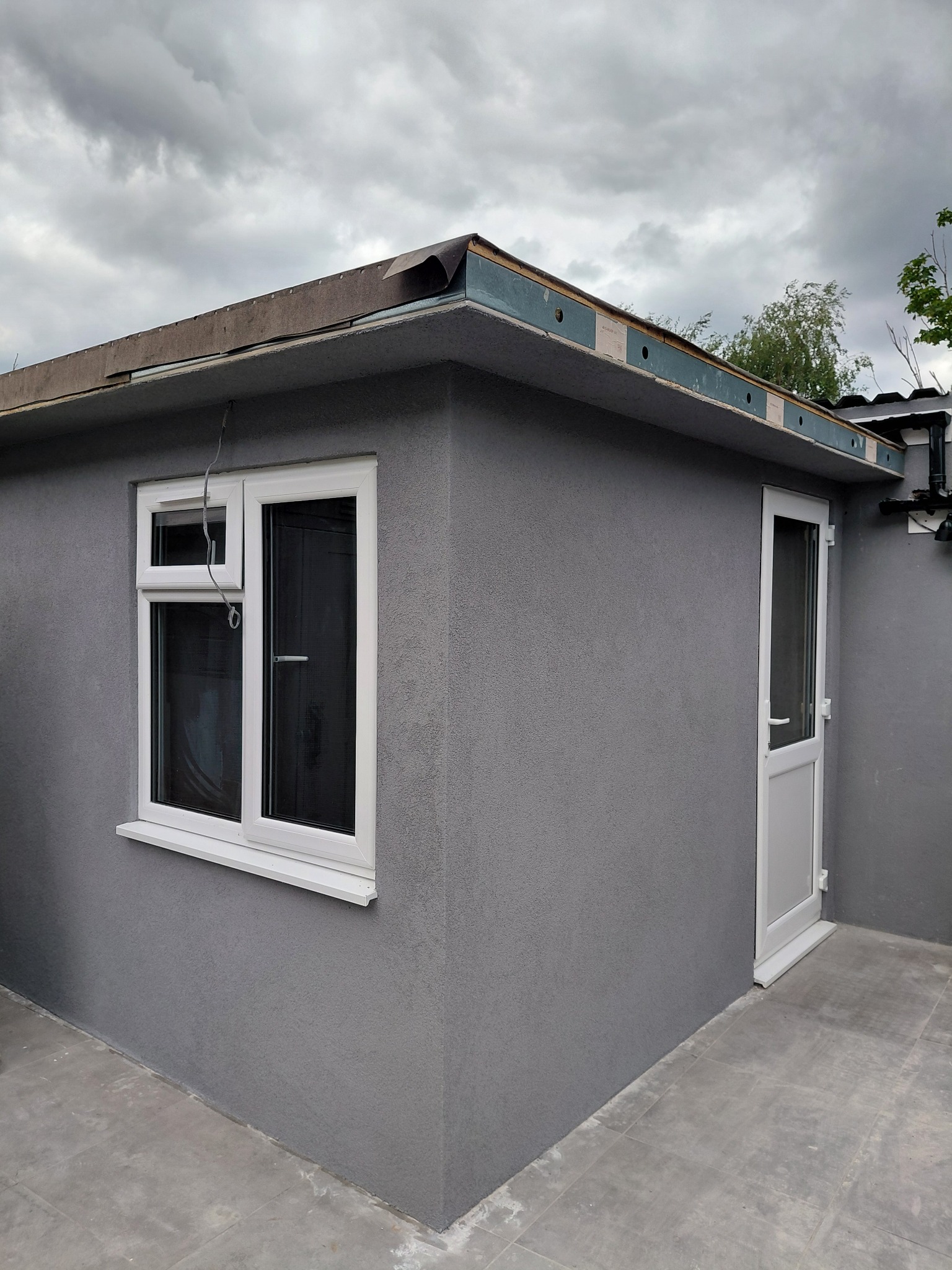 Grey textured render on an exterior extension with a white window
