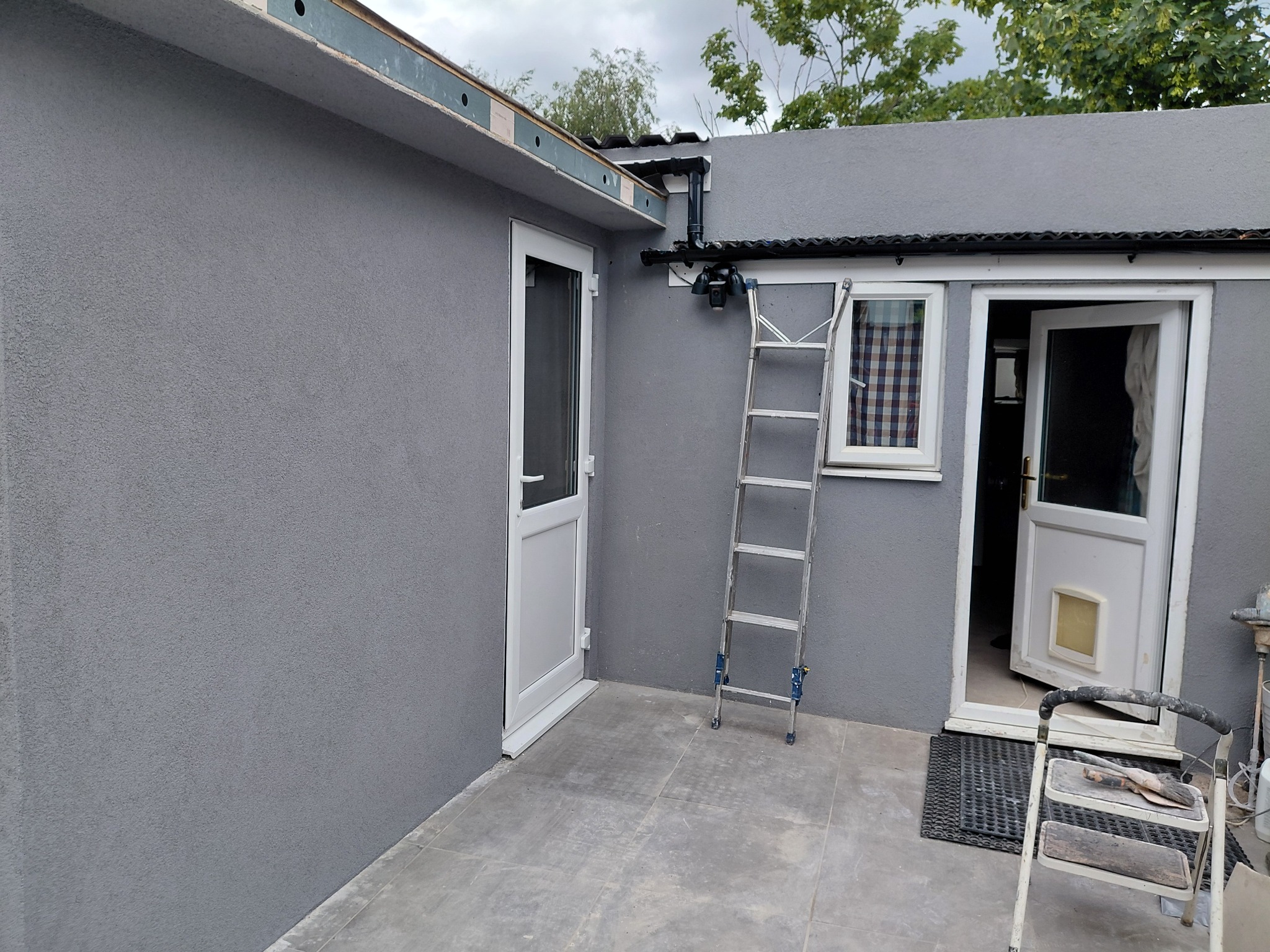 Grey rendered extension viewed from the paved rear area