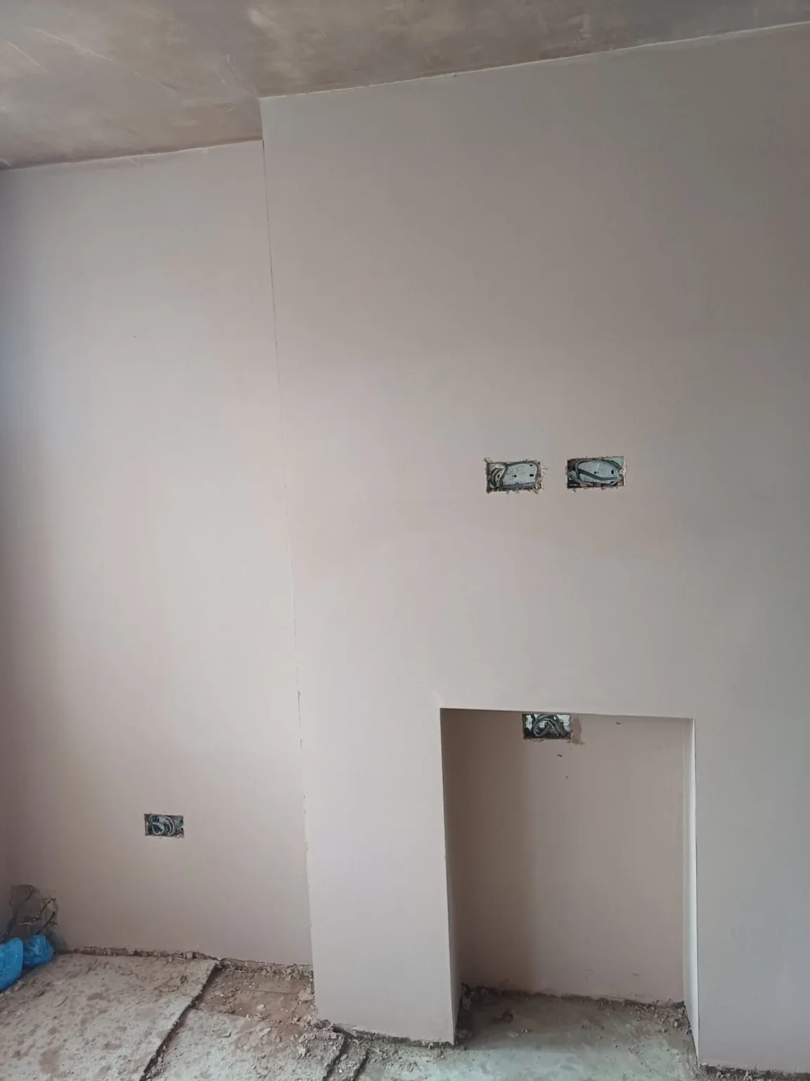 Plastered wall and recessed fireplace opening in a room