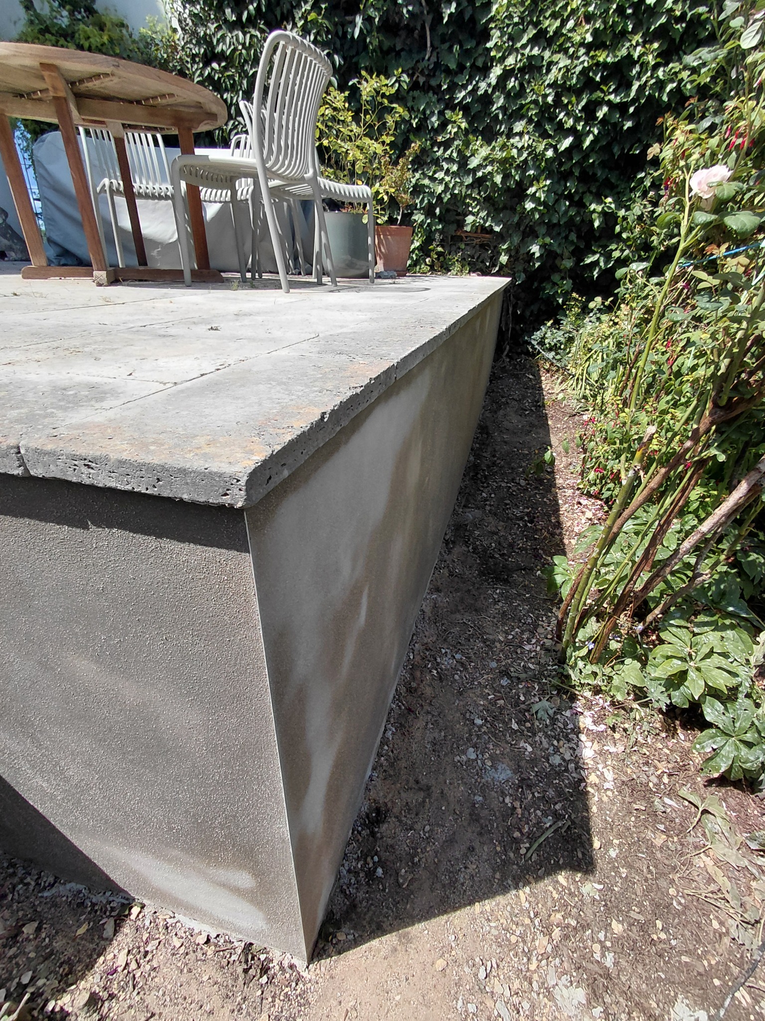 Cement render on a garden retaining wall beneath a paved edge
