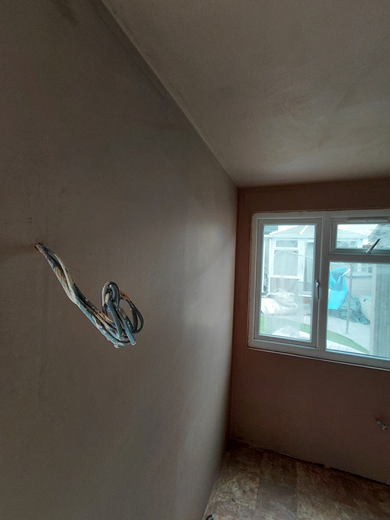 Fresh skim coat on a wall and ceiling beside a window
