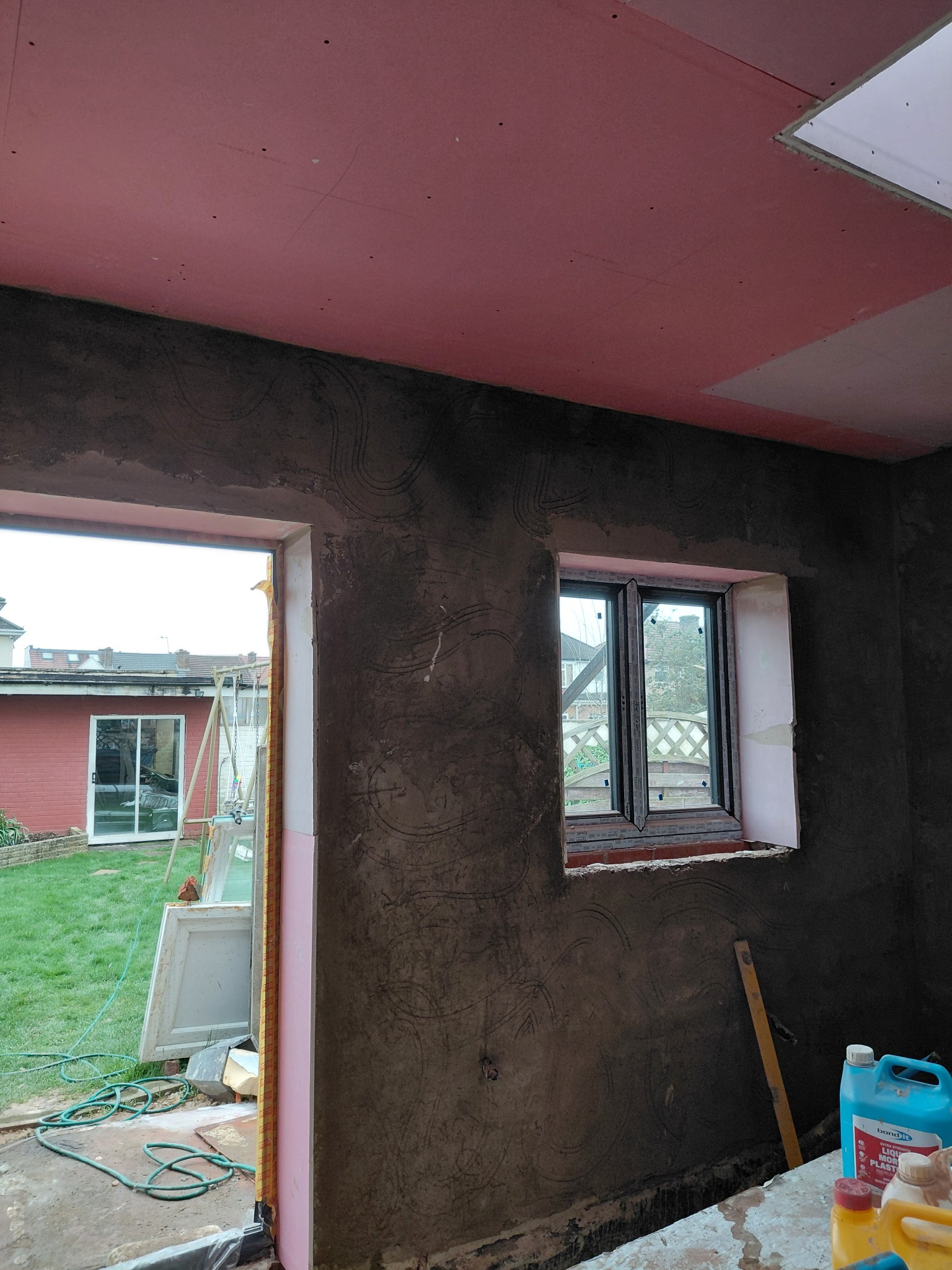 Dark sand and cement render on the walls of an unfinished room
