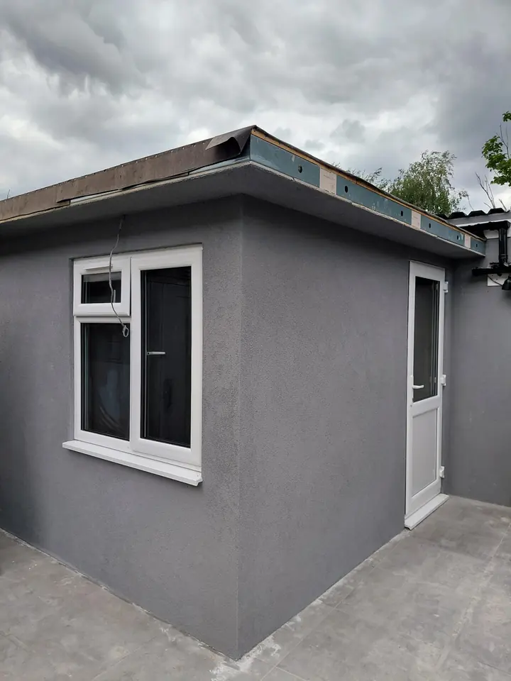 Grey textured render on an exterior extension with a white window